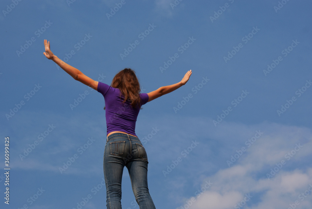 Young woman staying with raised hands against blue sky Young woman staying with raised hands against blue sky