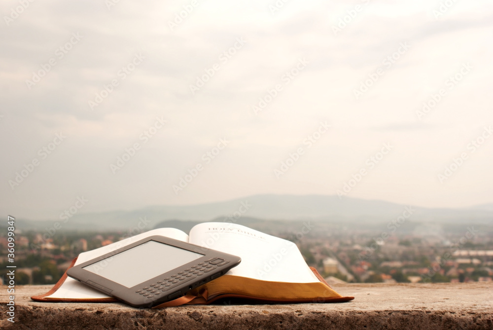 Electronic book reader laying on the book outdoors
