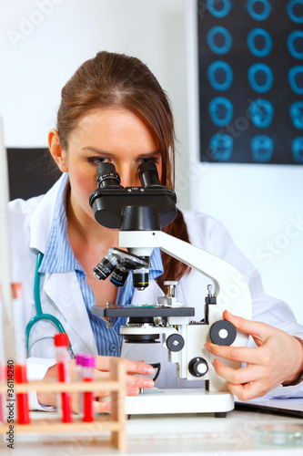 Female medical doctor using microscope in medical laboratory