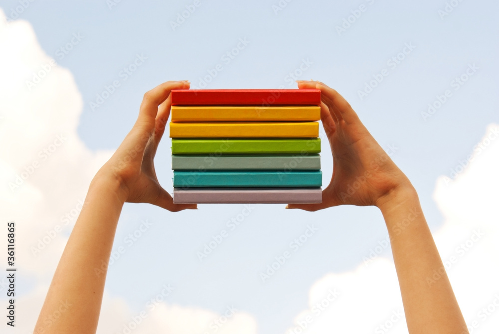 Hands holding colorful hard cover books