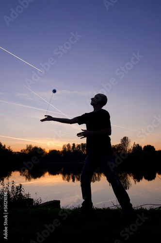 Silhouette of Yo-Yo player on the lake shore