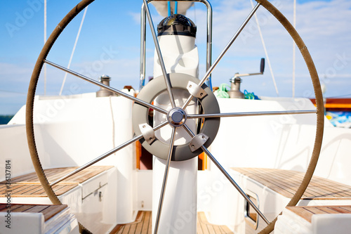A steering wheel on a boat with empty seats.
