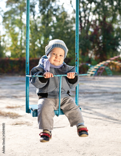 baby boy playing on swing in autumn park