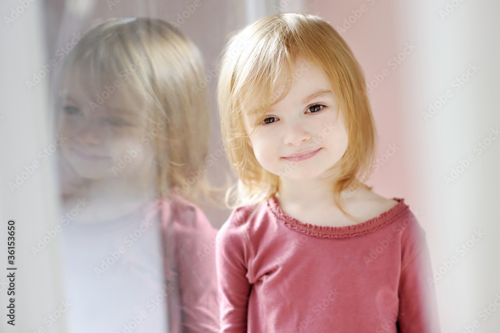 Fotografie Adorable smiling little girl by the window
