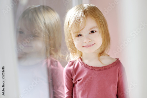 Fotografie Adorable smiling little girl by the window