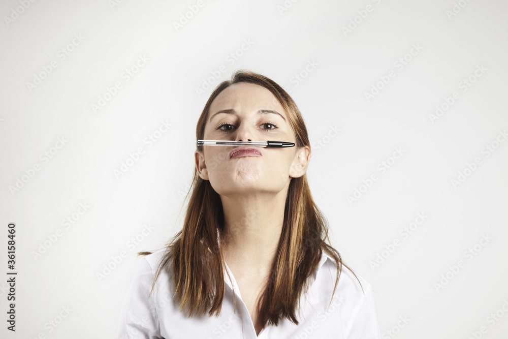 young businesswoman holding pen with his nose young businesswoman holding pen with his nose