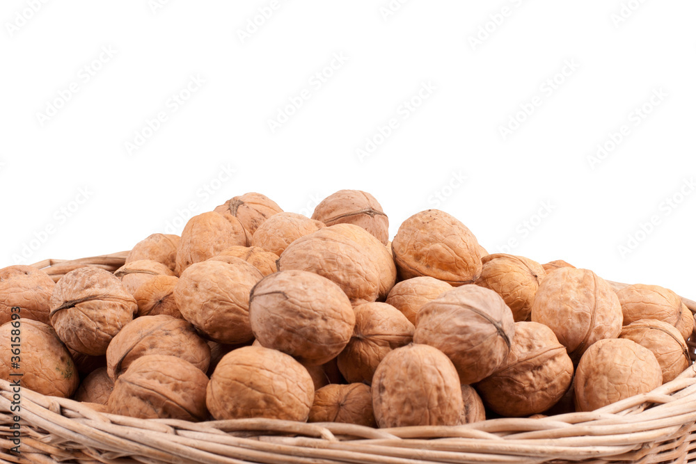Walnuts in wooden basket on the white background Walnuts in wooden basket on the white background