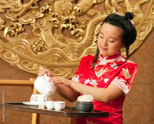 A Chinese girl in traditional dress making tea