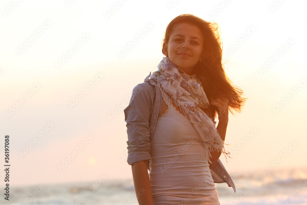 Obraz premium young attractive woman on sunset sea background