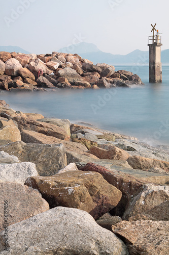 Lighthouse on a Rocky Breakwall: A small lighthouse warns of a r © Cozyta