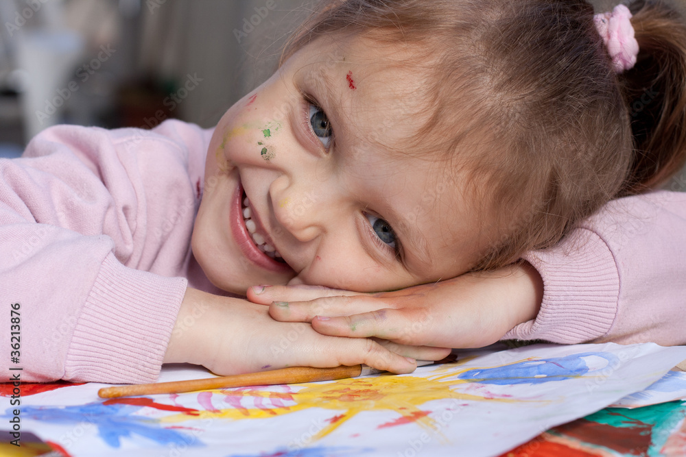 Happy little artist. Smiling little girl with painting and paint on her hands and face resting her head on her hands Happy little artist. Smiling little girl with painting and paint on her hands and face resting her head on her hands
