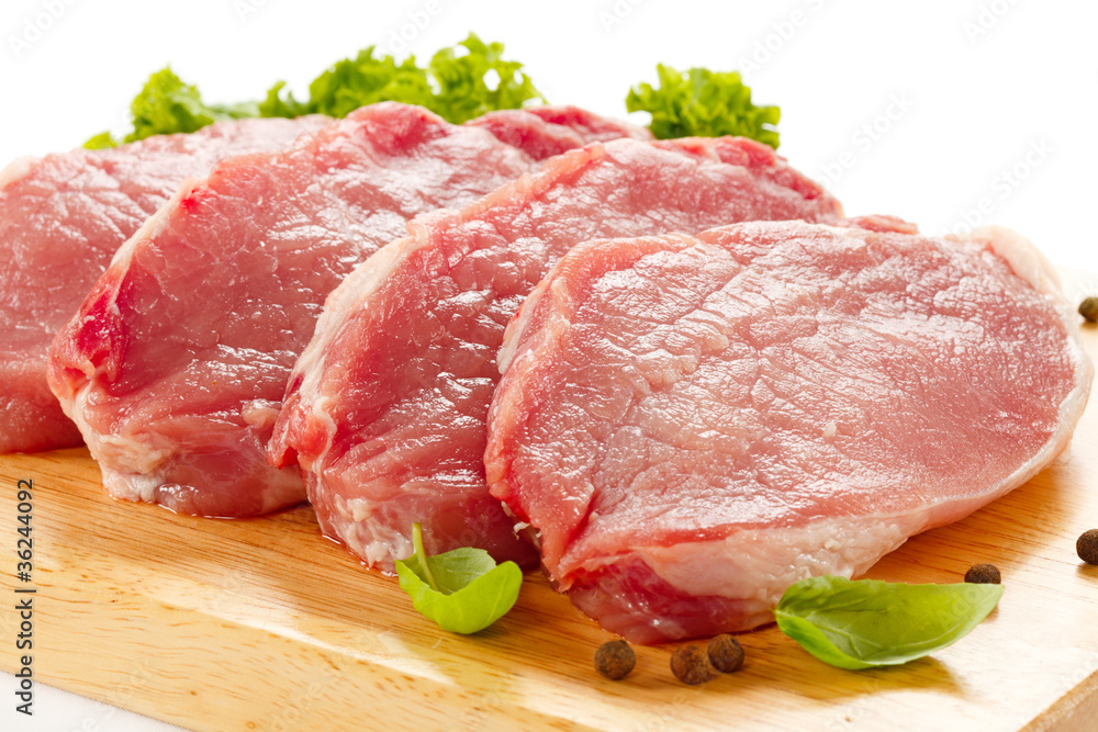 Raw pork on cutting board and vegetables