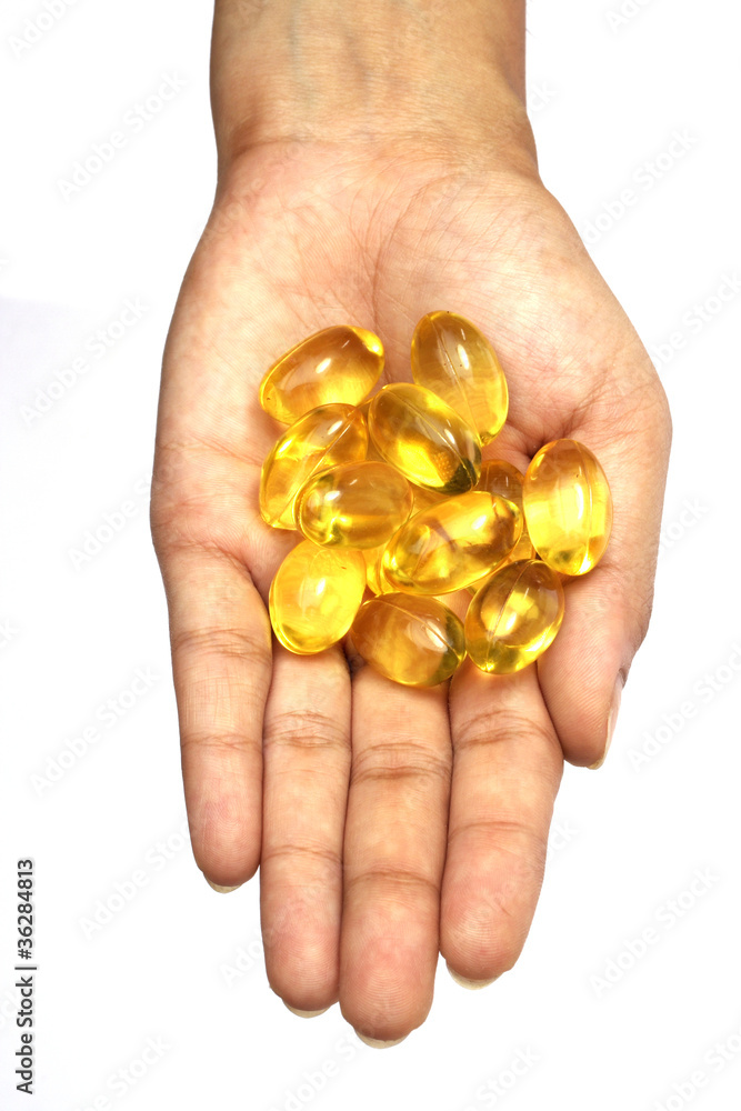 Cod liver oil pills in hand on white Cod liver oil pills in hand on white