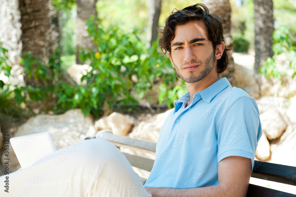 Portrait of a young man with laptop outdoor sitting on bench Portrait of a young man with laptop outdoor sitting on bench