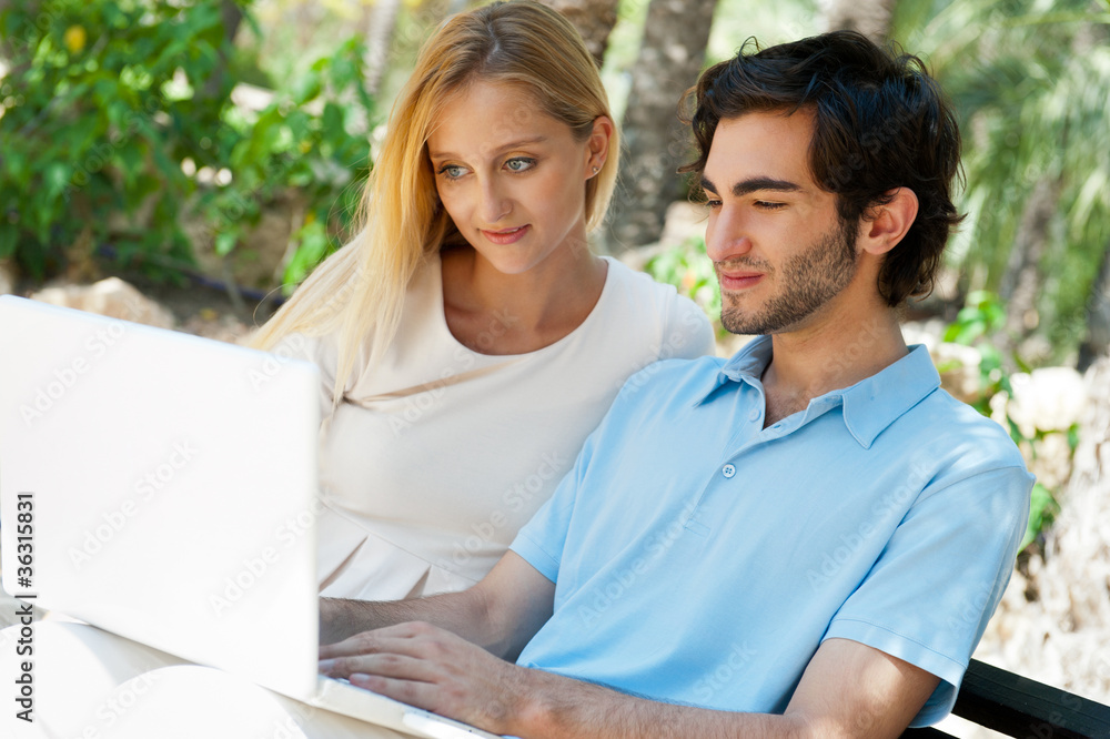 Young couple working on laptop and smiling while sitting relaxed Young couple working on laptop and smiling while sitting relaxed