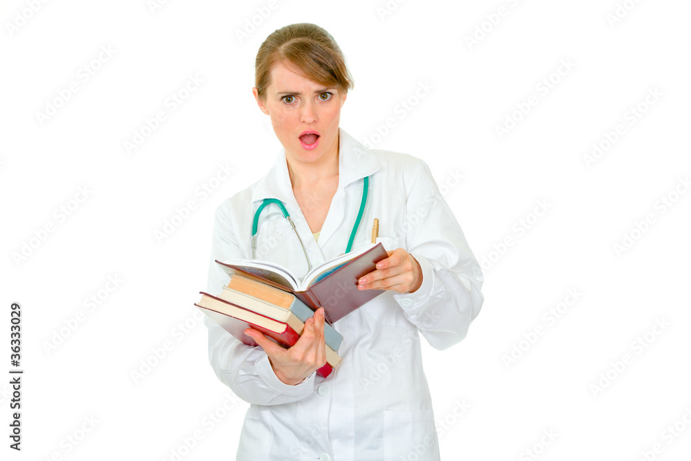 Confused medical female doctor with pile of books Confused medical female doctor with pile of books