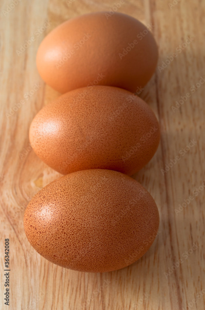 Three eggs on top the chopping board. Three eggs on top the chopping board.