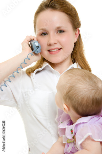 Businesswoman with a baby in her arms on the phone.