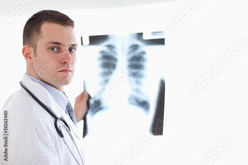 Serious looking doctor holding x-ray against light