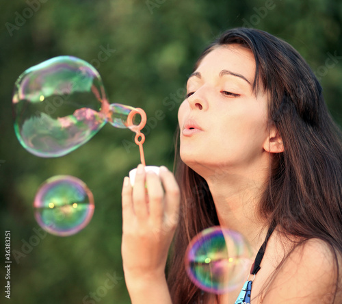 Pretty woman inflating soap-bubbles