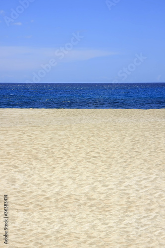 Sandstrand mit blauem Meer und Himmel im Hochformat