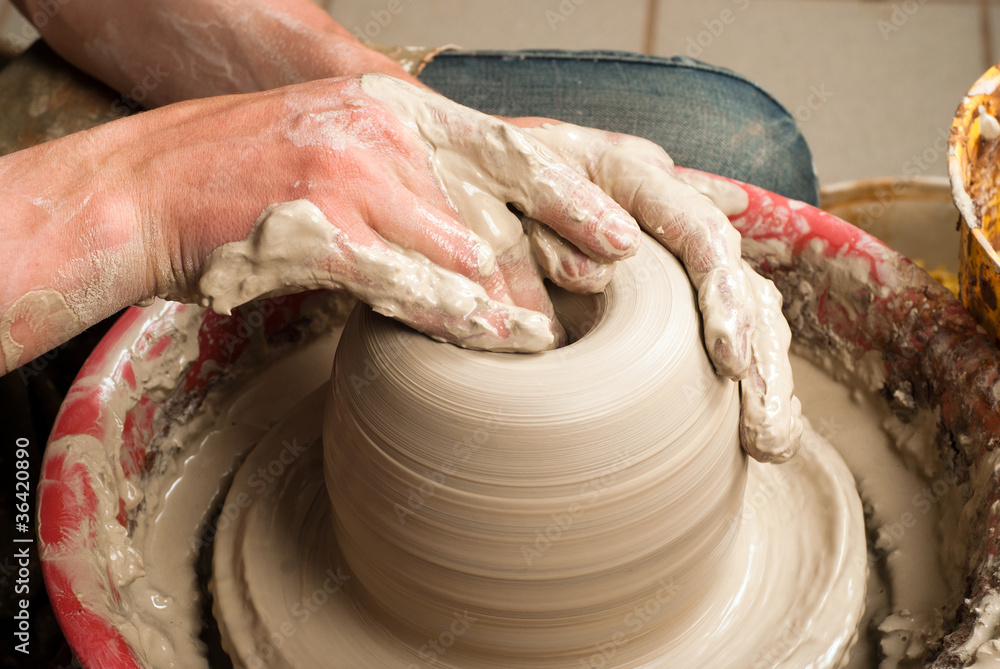 hands of a potter, creating an earthen jar on the circle