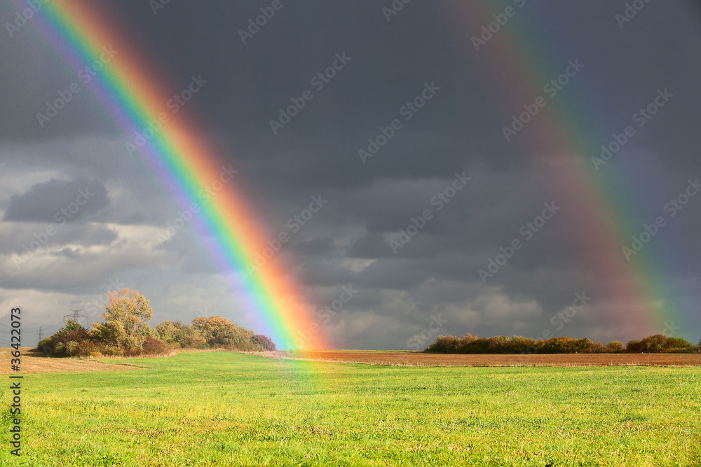 Natural two rainbow over green field and dark sky Natural two rainbow over green field and dark sky