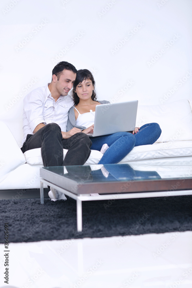 joyful couple relax and work on laptop computer at modern home joyful couple relax and work on laptop computer at modern home