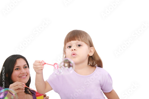 Portrait of funny lovely little girl blowing soap bubbles with h