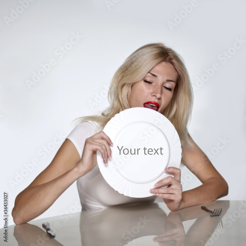 Blond woman licking plate. Copy space
