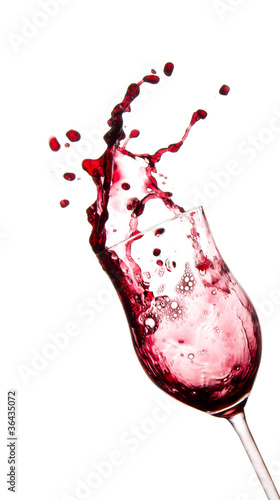Red wine splashing out of glass, isolated on white background