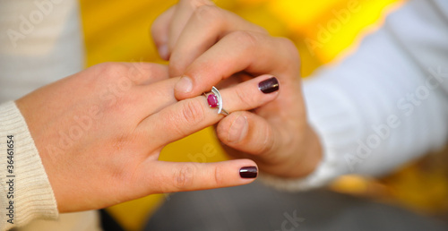 Boyfriend's arm putting on wedding ring to girlfriend's finger