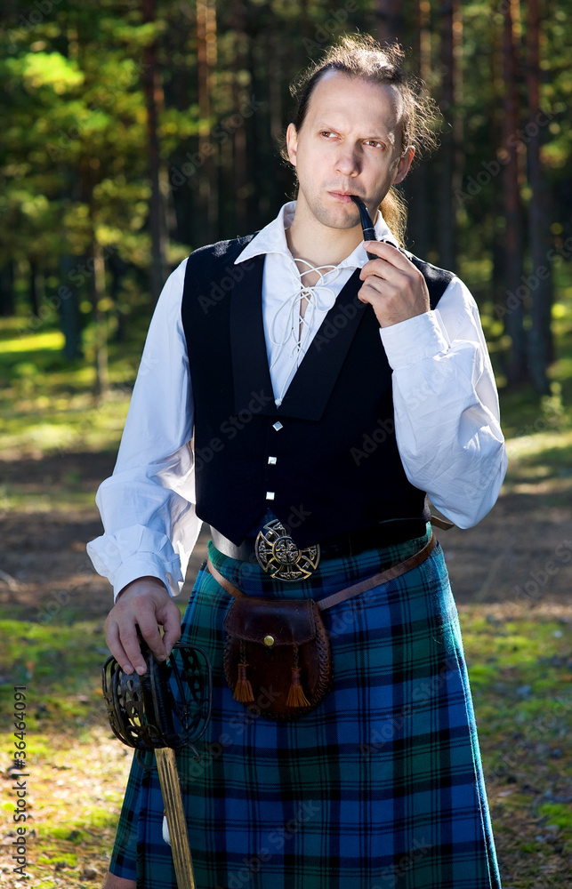 Fototapeta premium Man in scottish costume with sword and pipe