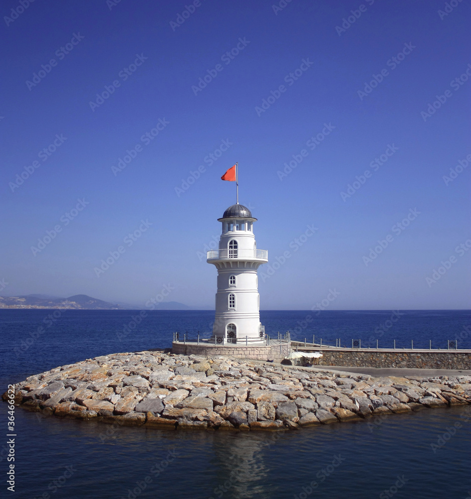 White beacon near coast with a red flag