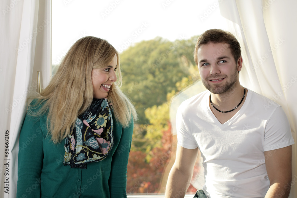 A happy young couple standing at the window