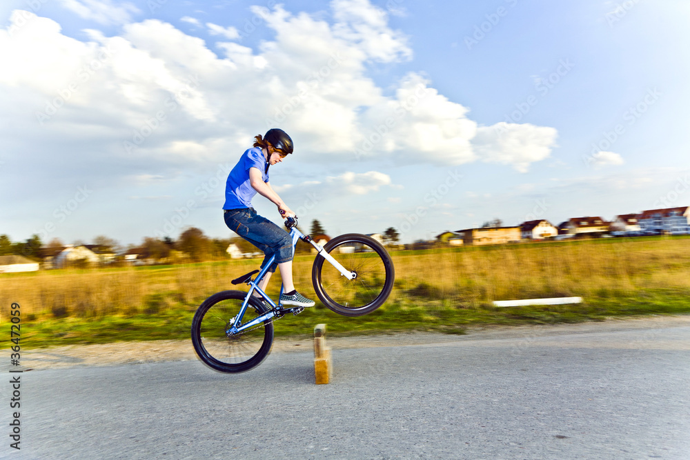 young boy jumping with his dirk bike over a barrier at the stree young boy jumping with his dirk bike over a barrier at the stree