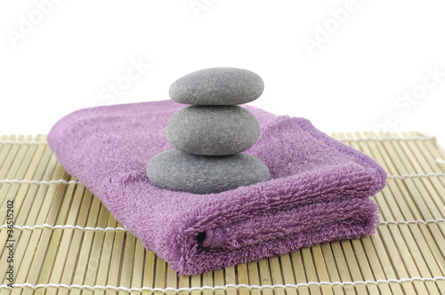 stones in balance on pink towel on bamboo stick straw mat