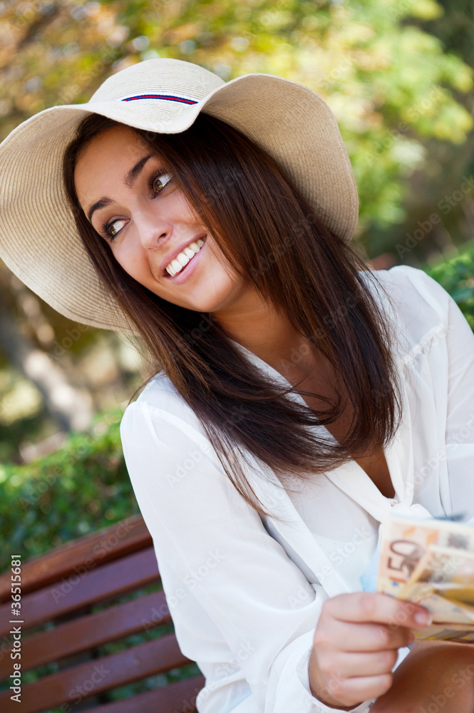 Portrait of young pretty woman sitting on bench at summer or aut