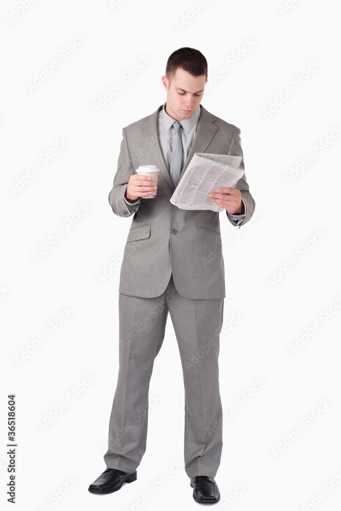 Portrait of a businessman reading the news while holding a cup o Portrait of a businessman reading the news while holding a cup o