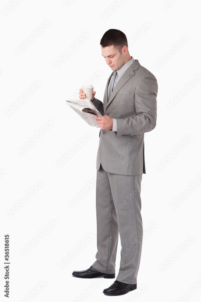Portrait of a businessman holding a cup of tea while reading the