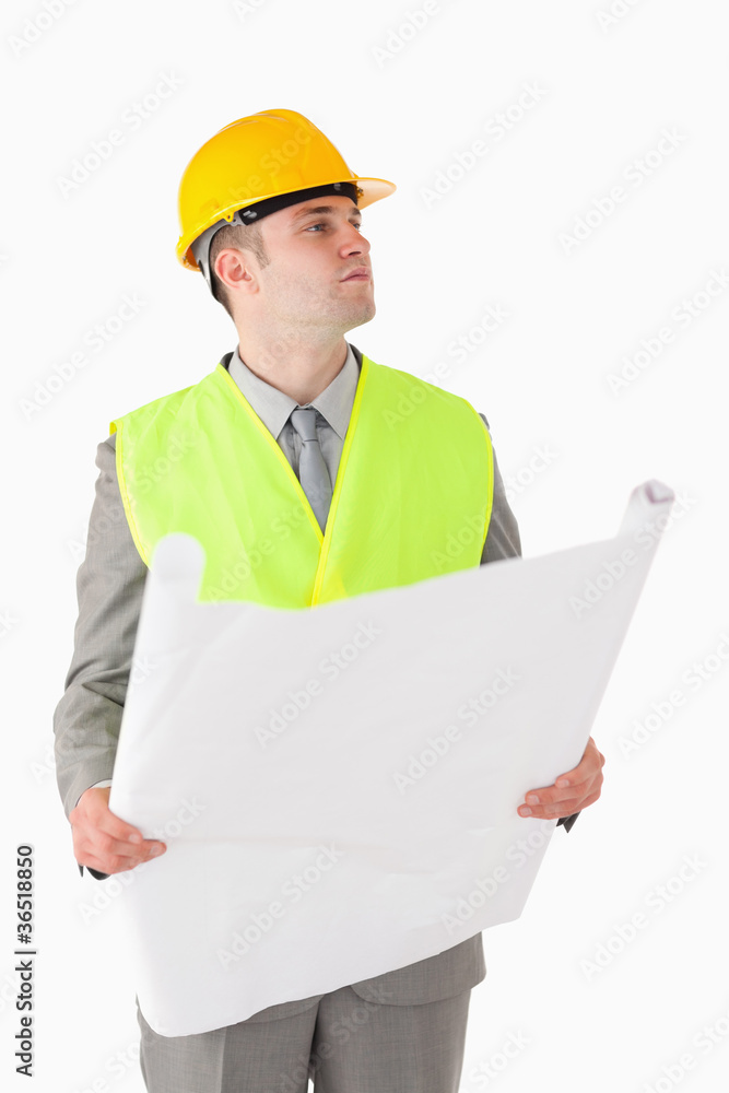 Portrait of a young builder looking around while holding a plan Portrait of a young builder looking around while holding a plan