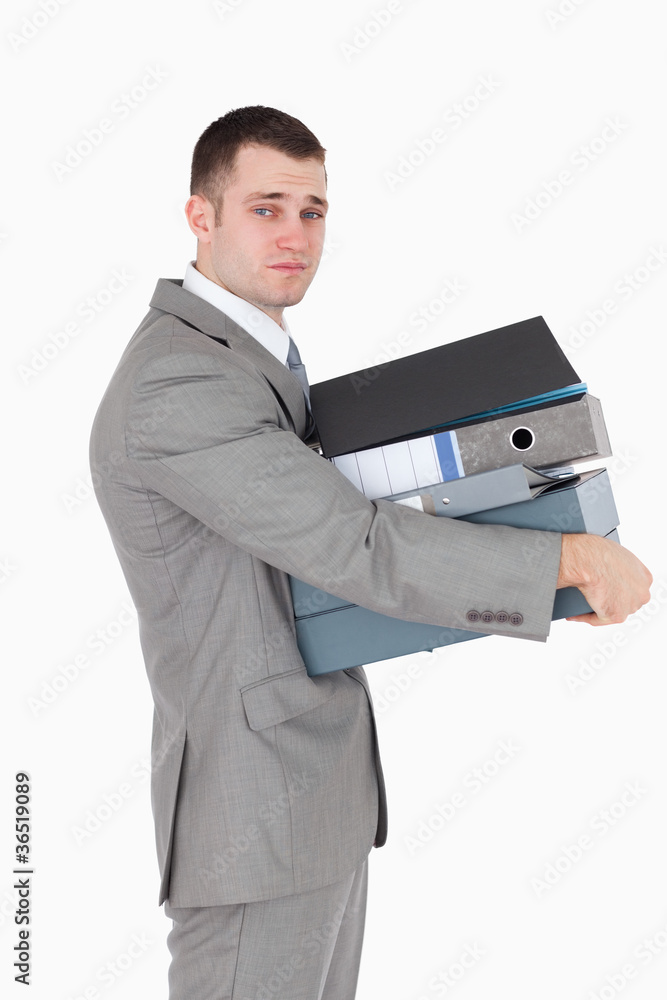 Portrait of a stressed businessman holding a stack of binders Portrait of a stressed businessman holding a stack of binders
