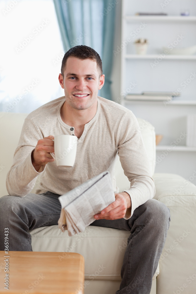 Portrait of a man holding a newspaper while drinking a tea