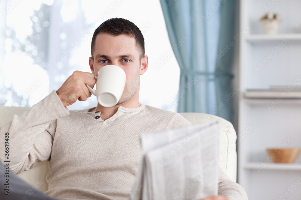 Handsome man having a tea while reading the news Handsome man having a tea while reading the news