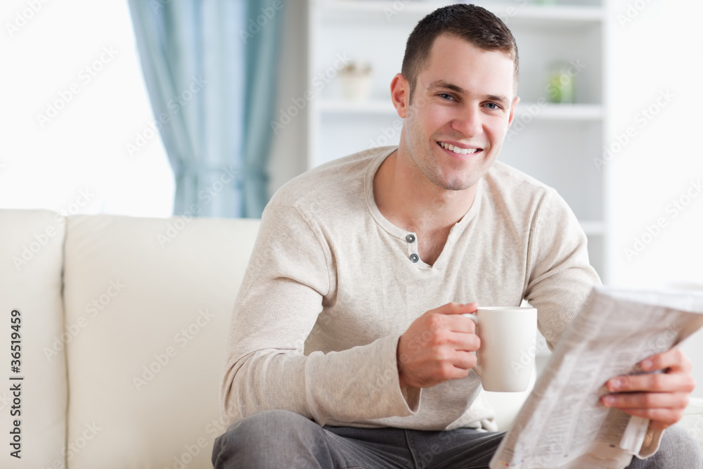 Happy man having a tea while reading the news