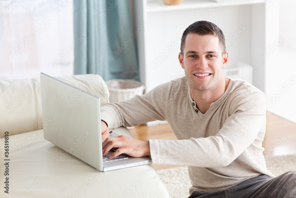 Smiling man sitting on a carpet posing with a notebook