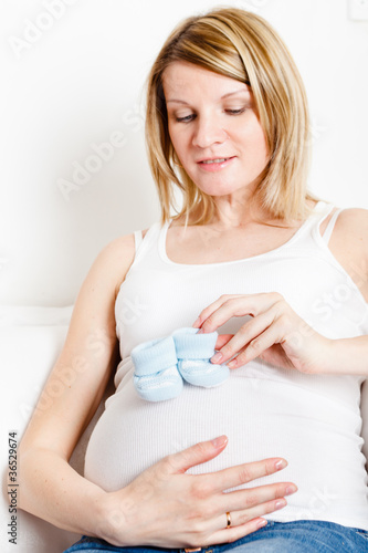 Beautiful pregnant woman with baby bootees, focus on belly