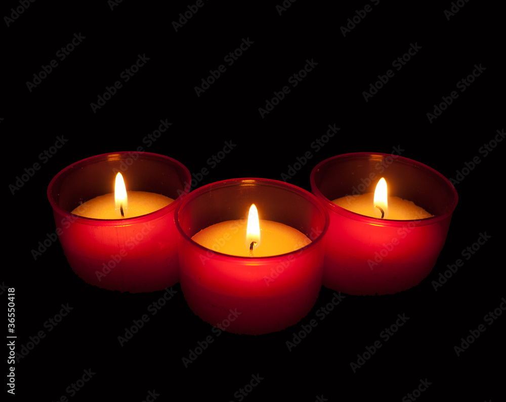 Votive candles in red holders over black Votive candles in red holders over black
