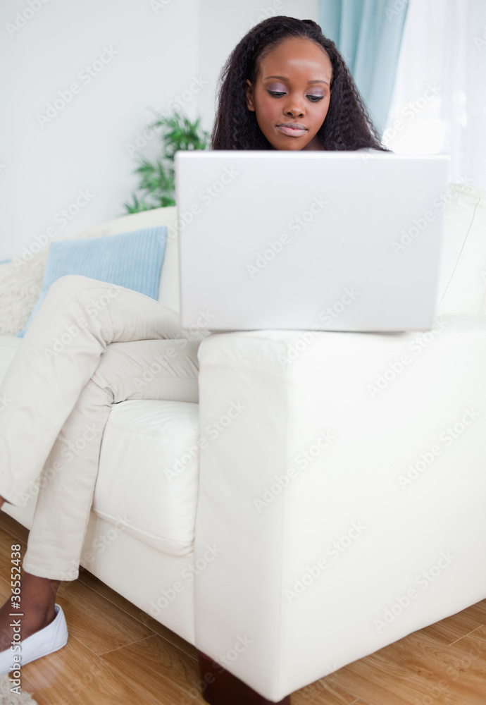 Woman working on laptop while sitting on sofa Woman working on laptop while sitting on sofa