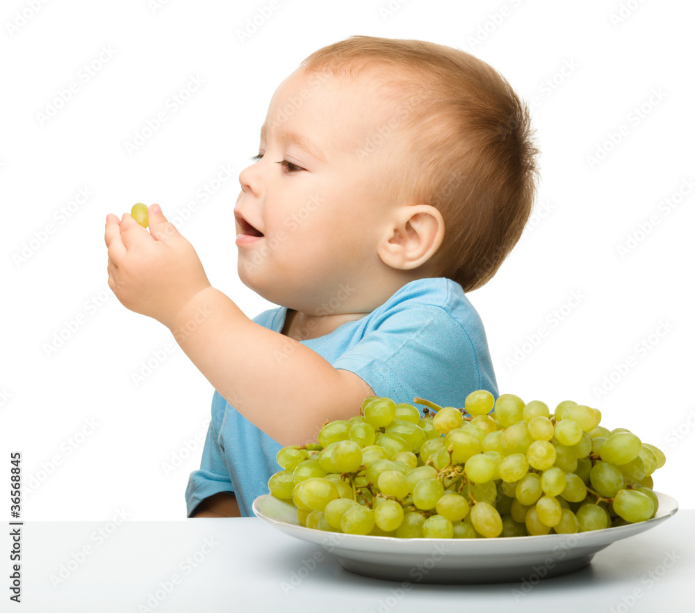 Little boy is eating grapes